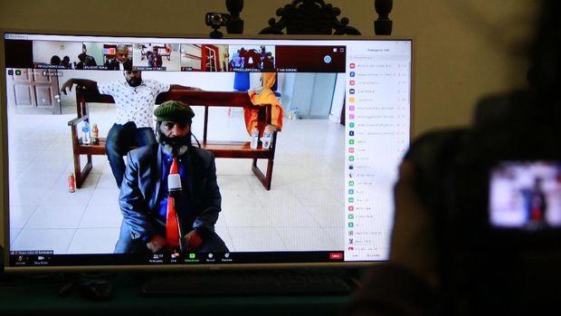 Buchtar Tabuni, a leading figure in Papua's independence movement, is seen on a monitor at a separate location due to the COVID-19 coronavirus outbreak as he sits in the dock during his trial in Balikpapan, East Kalimantan on June 17, 2020. - A group of Papuan activists were jailed by an Indonesian court on June 17, on treason charges linked to anti-racism protest in 2019, in a case that sparked fears about a clampdown on freedom of speech. (Photo by STR / AFP)