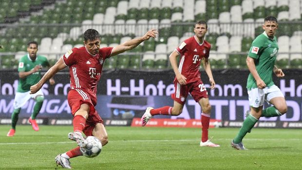 Bayern's Robert Lewandowski, left, scores his side's opening goal during the German Bundesliga soccer match between Werder Bremen and Bayern Munich in Bremen, Germany, Tuesday, June 16, 2020. Because of the coronavirus outbreak all soccer matches of the German Bundesliga take place without spectators. (AP Photo/Martin Meissner, Pool)