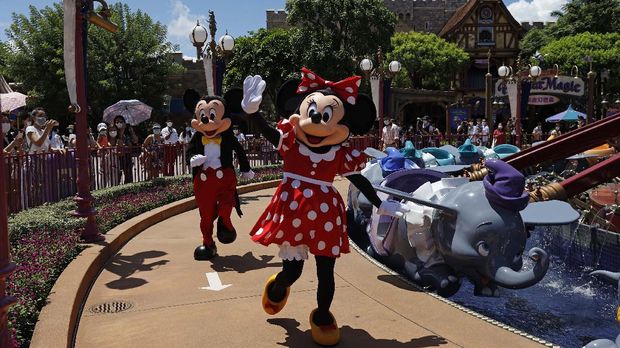 The iconic cartoon characters Minnie and Mickey Mouse wave to visitors at the Hong Kong Disneyland on Thursday, June 18, 2020. Hong Kong Disneyland on Thursday opened its doors to visitors for the first time in nearly five months, at a reduced capacity and with social distancing measures in place. The theme park closed temporarily at the end of January due to the coronavirus outbreak, and is the second Disney-themed park to re-open worldwide, after Shanghai Disneyland. (AP Photo/Kin Cheung)