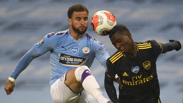 Arsenal's Eddie Nketiah, right, and Manchester City's Kyle Walker battle for the ball the English Premier League soccer match between Manchester City and Arsenal at the Etihad Stadium in Manchester, England, Wednesday, June 17, 2020. The English Premier League resumes Wednesday after its three-month suspension because of the coronavirus outbreak. (Peter Powell/Pool via AP)