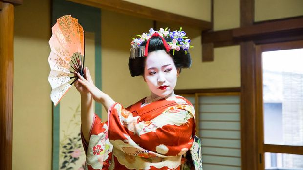 Maiko girl dancing with paper fan in Japanese tatami room