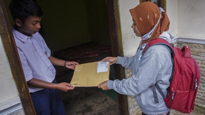 JEMPUT BOLA TUGAS SEKOLAH SAAT PANDEMI COVID-19 Kepala Sekolah SMP N 4 Bawang Mulud Sugito (tengah) dan guru Wiyata Bhakti bersiap melewati aliran sungai di dasar bukit saat mengantar lembar tugas siswa secara langsung ke rumahnya di Pranten, Kecamatan Bawang, Kabupaten Batang, Jawa Tengah.