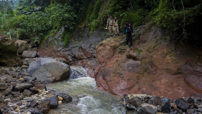 Kepala Sekolah SMP N 4 Bawang Mulud Sugito (tengah) dan guru Wiyata Bhakti bersiap melewati aliran sungai di dasar bukit saat mengantar lembar tugas siswa secara langsung ke rumahnya di Pranten, Kecamatan Bawang, Kabupaten Batang, Jawa Tengah.
