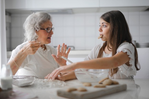 Ibu dan anak sedang membuat kue sambil berbicara satu sama lain