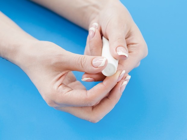 Gambar wanita menggunakan hand cream dalam bentuk tube.