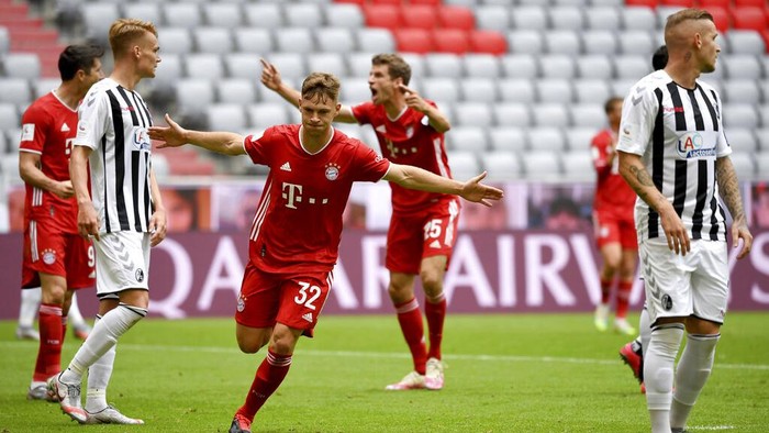 Munichs Joshua Kimmich, center, cheers after his opening goal during a German Bundesliga soccer match between Bayern Munich and SC Freiburg in Munich, Germany, Saturday, June, 20, 2020. (Sven Hoppe/dpa via AP)