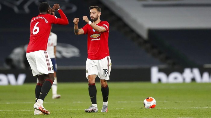 Manchester Uniteds Bruno Fernandes, right, celebrates with Paul Pogba after scoring his sides first goal during the English Premier League soccer match between Tottenham Hotspur and Manchester United at Tottenham Hotspur Stadium in London, England, Friday, June 19, 2020. (AP Photo/Matt Childs, Pool)