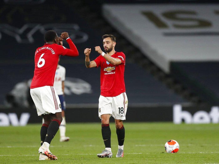Manchester Uniteds Bruno Fernandes, right, celebrates with Paul Pogba after scoring his sides first goal during the English Premier League soccer match between Tottenham Hotspur and Manchester United at Tottenham Hotspur Stadium in London, England, Friday, June 19, 2020. (AP Photo/Matt Childs, Pool)