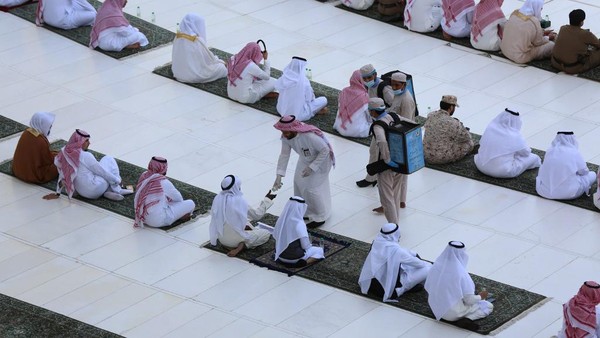 This picture taken early on May 24, 2020 shows a local official handing out bottles of Zamzam water to worshippers gathering in rows before the Kaaba at the Grand Mosque in Saudi Arabias holy city of Mecca to attend the prayers of Eid al-Fitr, the Muslim holiday which starts at the conclusion of the holy fasting month of Ramadan. - Saudi Arabia began a five-day, round-the-clock curfew from May 23 after COVID-19 coronavirus infections more than quadrupled since the start of Ramadan to around 68,000 -- the highest in the Gulf. (Photo by - / AFP)