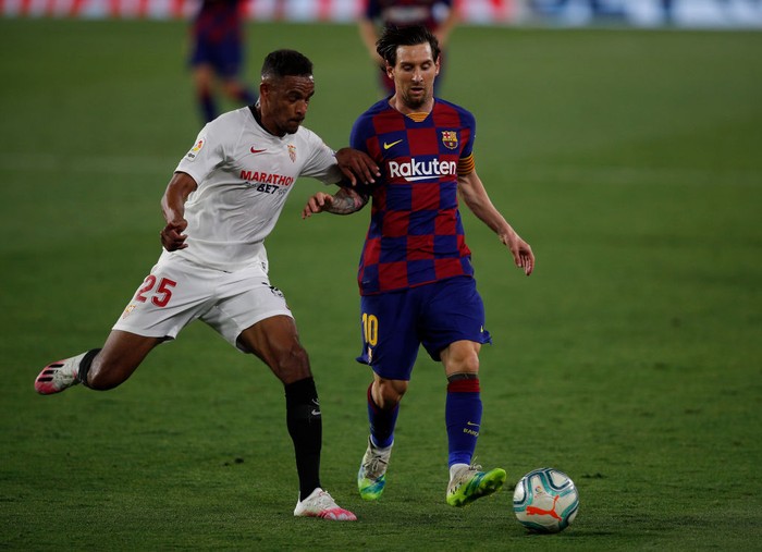 SEVILLE, SPAIN - JUNE 19: Lionel Messi of Barcelona is challenged by Fernando of Sevilla  during the Liga match between Sevilla FC and FC Barcelona at Estadio Ramon Sanchez Pizjuan on June 19, 2020 in Seville, Spain. (Photo by Fran Santiago/Getty Images)