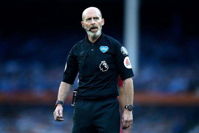 LIVERPOOL, ENGLAND - JUNE 21: Match referee Mike Dean looks on while the NHS logo is seen on his shirt during the Premier League match between Everton FC and Liverpool FC at Goodison Park on June 21, 2020 in Liverpool, England. Football Stadiums around Europe remain empty due to the Coronavirus Pandemic as Government social distancing laws prohibit fans inside venues resulting in all fixtures being played behind closed doors. (Photo by Peter Powell/Pool via Getty Images)