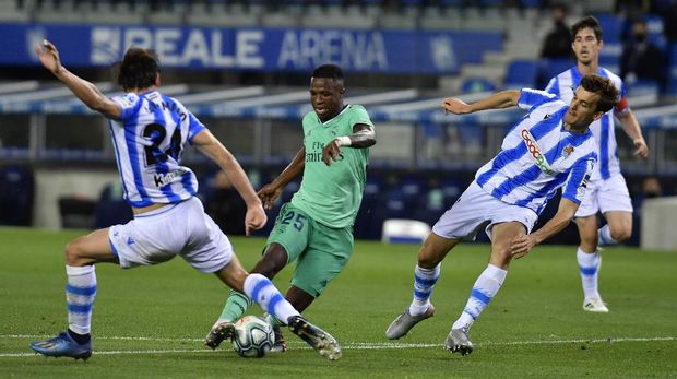 Real Madrid's Vinicius Junior, centre, controls the ball past Real Sociedad's Robin Le Normand during the Spanish La Liga soccer match between Real Sociedad and Real Madrid at Anoeta stadium, San Sebastian, Spain, Sunday, June 21, 2020. (AP Photo/Alvaro Barrientos)