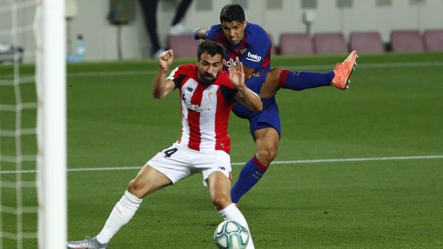 Barcelona's Luis Suarez, right, kicks the ball next to Athletic Bilbao's Dani Garcia during the Spanish La Liga soccer match between FC Barcelona and Athletic Bilbao at the Camp Nou stadium in Barcelona, Spain, Tuesday, June 23, 2020. (AP Photo/Joan Monfort)