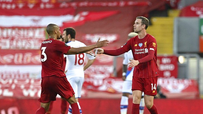 Liverpools Jordan Henderson, right, hands the captains armband to Liverpools Fabinho as he is substituted during the English Premier League soccer match between Liverpool and Crystal Palace at Anfield Stadium in Liverpool, England, Wednesday, June 24, 2020. (Paul Ellis/Pool via AP)