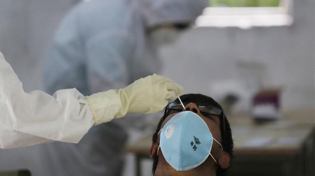 A health worker takes a nasal sample for the COVID-19 rapid antigen test in New Delhi, India, Friday, June 19, 2020. Delhi government commenced COVID 19 testing through rapid antigen methodology in and around containment zones of the capital with a sharp rise in caseloads. (AP Photo/Manish Swarup)