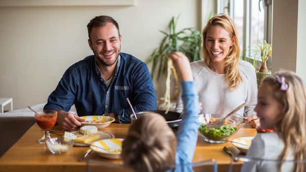 Happy family enjoying lunch while kids playing.