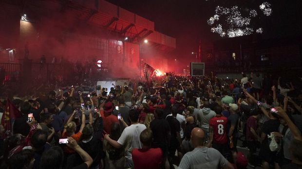 Liverpool supporters celebrate as they gather outside of Anfield Stadium in Liverpool, England, Thursday, June 25, 2020 after Liverpool clinched the English Premier League title. Liverpool took the title after Manchester City failed to beat Chelsea on Wednesday evening. (AP photo/Jon Super)