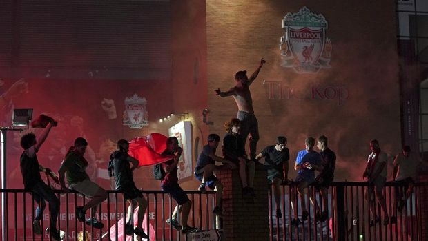 Liverpool supporters celebrate as they gather outside of Anfield Stadium in Liverpool, England, Thursday, June 25, 2020 after Liverpool clinched the English Premier League title. Liverpool took the title after Manchester City failed to beat Chelsea on Wednesday evening. (AP photo/Jon Super)