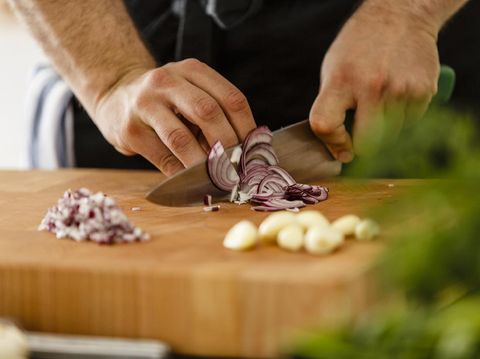 Close up male hands chopped fresh red onion on wooden table