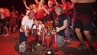 Suporter Liverpool berpesta dengan membawa replika tropi Liga Inggris dan Liga Champions.