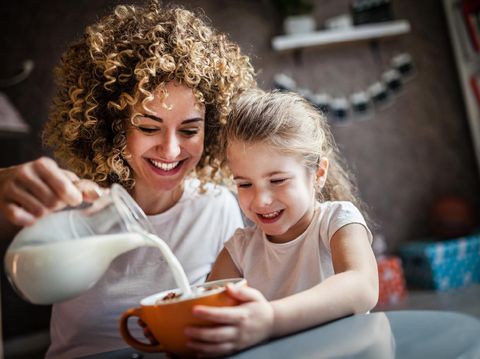 Portrait of adorable young girl and mother having breakfast