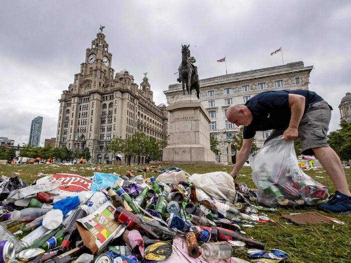 A workman clears up rubbish outside the Liver building in Liverpool after fans celebrated in the city last night following Liverpool FC winning the Premier League on Thursday night, Saturday June 27, 2020. (Peter Byrne/PA via AP)