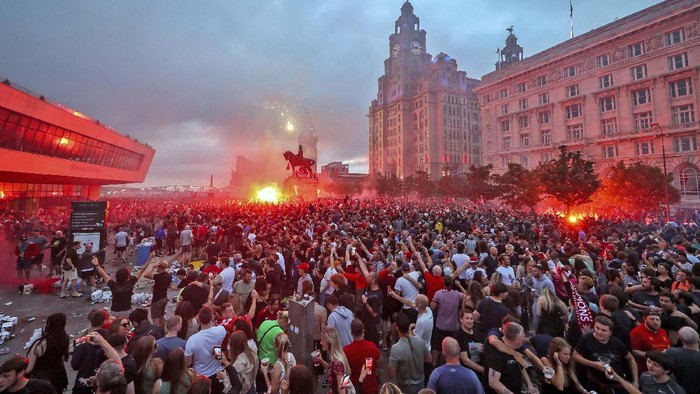 A workman clears up rubbish outside the Liver building in Liverpool after fans celebrated in the city last night following Liverpool FC winning the Premier League on Thursday night, Saturday June 27, 2020. (Peter Byrne/PA via AP)