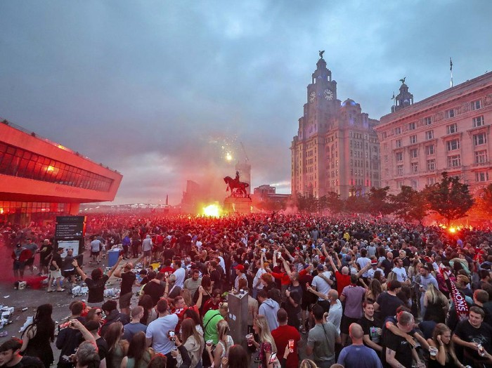 A workman clears up rubbish outside the Liver building in Liverpool after fans celebrated in the city last night following Liverpool FC winning the Premier League on Thursday night, Saturday June 27, 2020. (Peter Byrne/PA via AP)