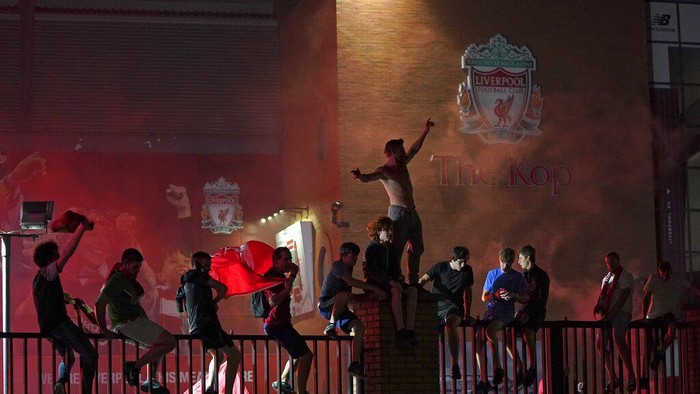 Liverpool supporters celebrate as they gather outside of Anfield Stadium in Liverpool, England, Thursday, June 25, 2020 after Liverpool clinched the English Premier League title. Liverpool took the title after Manchester City failed to beat Chelsea on Wednesday evening. (AP photo/Jon Super)