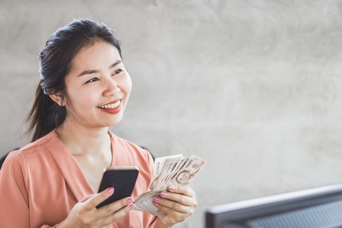 zodiak happy Asian woman hand holding smart phone and banknotes ,make money online concept