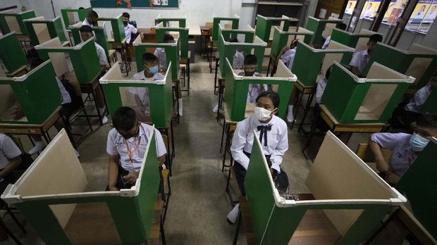 Students in a protective gear are seated at partitioned desks at the Samkhok School in Pathum Thani, outside Bangkok, Wednesday, July 1, 2020. Thailand has begun a fifth phase of relaxations of COVID-19 restrictions, allowing the reopening of schools and high-risk entertainment venues such as pubs and massage parlors that had been shut since mid-March. (AP Photo/Sakchai Lalit)