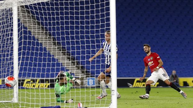 Manchester United's Bruno Fernandes, right, scores his side's third goal during the English Premier League soccer match between Brighton & Hove Albion and Manchester United at the AMEX Stadium in Brighton, England, Tuesday, June 30, 2020. (AP Photo/Alastair Grant, Pool)