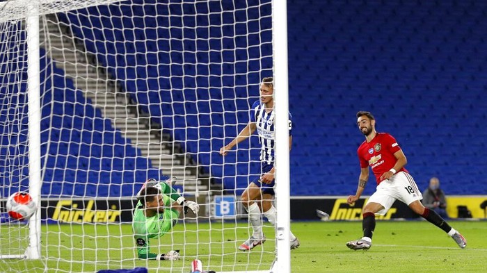 Manchester Uniteds Bruno Fernandes, right, scores his sides third goal during the English Premier League soccer match between Brighton & Hove Albion and Manchester United at the AMEX Stadium in Brighton, England, Tuesday, June 30, 2020. (AP Photo/Alastair Grant, Pool)