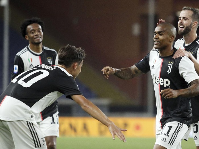 Juventus' Juan Cuadrado, right, in action during an Italian Serie A soccer match between Genoa and Juventus at the Luigi Ferraris stadium in Genoa, Italy, Tuesday, June 30, 2020. (Tano Pecoraro/LaPresse via AP)