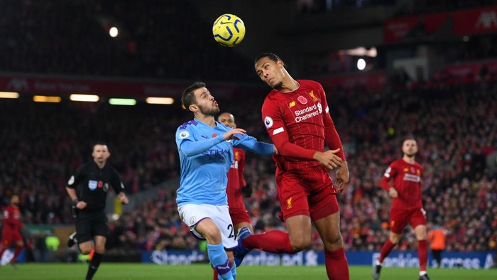 LIVERPOOL, ENGLAND - NOVEMBER 10: Virgil van Dijk of Liverpool heads the ball clear as he is put under pressure by Bernardo Silva of Manchester City during the Premier League match between Liverpool FC and Manchester City at Anfield on November 10, 2019 in Liverpool, United Kingdom. (Photo by Laurence Griffiths/Getty Images)