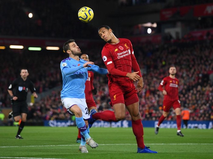 LIVERPOOL, ENGLAND - NOVEMBER 10: Virgil van Dijk of Liverpool heads the ball clear as he is put under pressure by Bernardo Silva of Manchester City during the Premier League match between Liverpool FC and Manchester City at Anfield on November 10, 2019 in Liverpool, United Kingdom. (Photo by Laurence Griffiths/Getty Images)