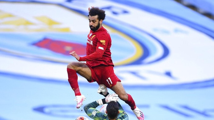 Liverpools Mohamed Salah leaps over Manchester Citys goalkeeper Ederson during the English Premier League soccer match between Manchester City and Liverpool at Etihad Stadium in Manchester, England, Thursday, July 2, 2020. (AP Photo/Laurence Griffiths,Pool)