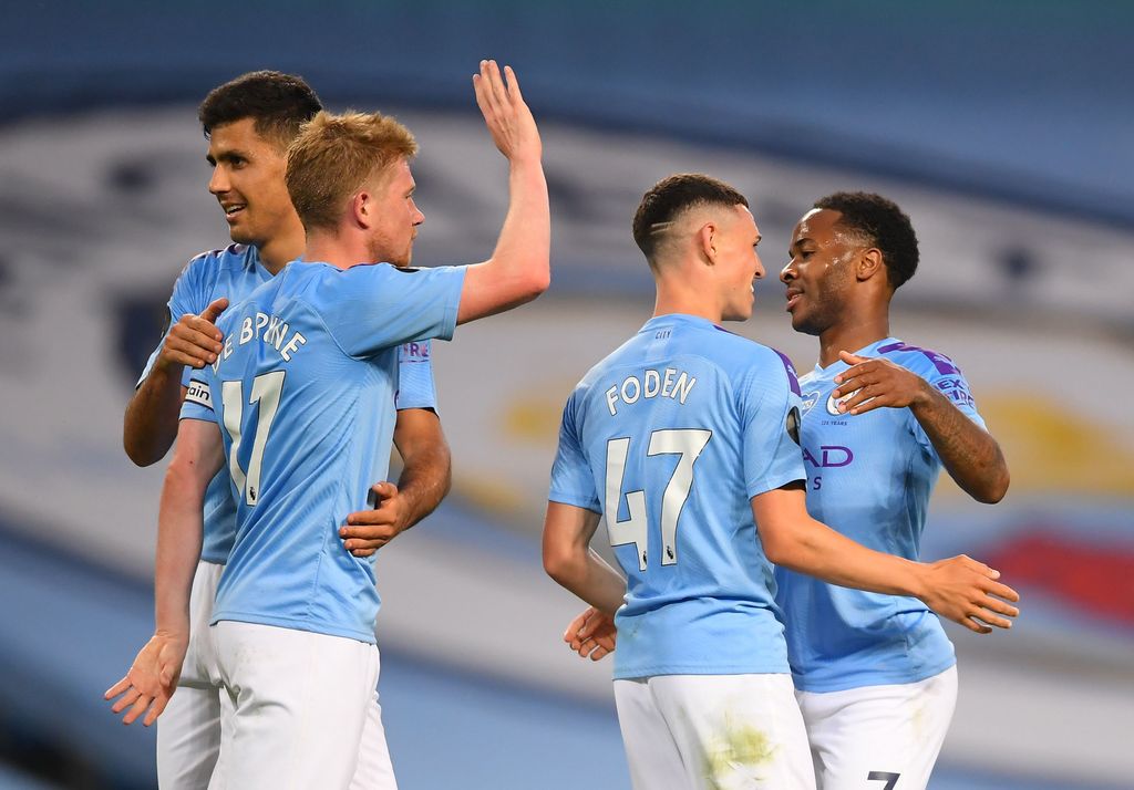 MANCHESTER, ENGLAND - JULY 02: Raheem Sterling of Manchester City celebrates his sides fourth goal which came through a Alex Oxlade-Chamberlain of Liverpool (not pictured) own goal with Kevin De Bruyne, Rodrigo and Phil Foden during the Premier League match between Manchester City and Liverpool FC at Etihad Stadium on July 02, 2020 in Manchester, England. Football Stadiums around Europe remain empty due to the Coronavirus Pandemic as Government social distancing laws prohibit fans inside venues resulting in all fixtures being played behind closed doors. (Photo by Laurence Griffiths/Getty Images)