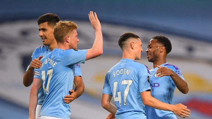 manchester city liverpool premier league liga inggris kevin de bruyne raheem stering phil foden MANCHESTER, ENGLAND - JULY 02: Raheem Sterling of Manchester City celebrates his sides fourth goal which came through a Alex Oxlade-Chamberlain of Liverpool (not pictured) own goal with Kevin De Bruyne, Rodrigo and Phil Foden during the Premier League match between Manchester City and Liverpool FC at Etihad Stadium on July 02, 2020 in Manchester, England. Football Stadiums around Europe remain empty due to the Coronavirus Pandemic as Government social distancing laws prohibit fans inside venues resulting in all fixtures being played behind closed doors. (Photo by Laurence Griffiths/Getty Images)