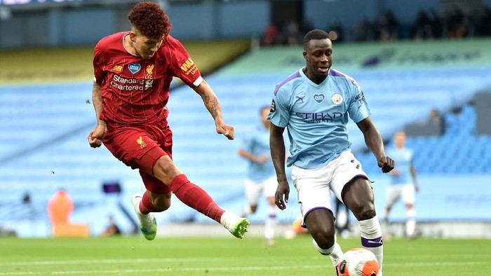 MANCHESTER, ENGLAND - JULY 02: Roberto Firmino of Liverpool shoots as he is challenged by Benjamin Mendy of Manchester City during the Premier League match between Manchester City and Liverpool FC at Etihad Stadium on July 02, 2020 in Manchester, England. Football Stadiums around Europe remain empty due to the Coronavirus Pandemic as Government social distancing laws prohibit fans inside venues resulting in all fixtures being played behind closed doors. (Photo by Peter Powell/Pool via Getty Images)