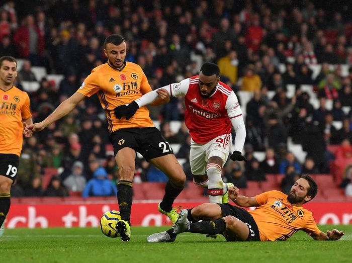 Arsenal, Wolverhampton Wanderers LONDON, ENGLAND - NOVEMBER 02: Alexandre Lacazette of Arsenal is tackled by Joao Moutinho of Wolverhampton Wanderers and Romain Saiss of Wolverhampton Wanderers during the Premier League match between Arsenal FC and Wolverhampton Wanderers at Emirates Stadium on November 02, 2019 in London, United Kingdom. (Photo by Justin Setterfield/Getty Images)