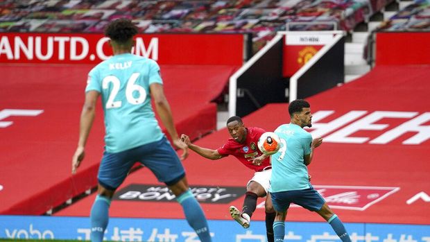 Manchester United's Anthony Martial, center, gets a shot off between Bournemouth's Dominic Solanke (9) and Lloyd Kelly (26) while scoring a goal during the English Premier League soccer match between Manchester United and Bournemouth at Old Trafford stadium in Manchester, England, Saturday, July 4, 2020. (Dave Thompson/Pool via AP)