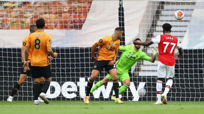 WOLVERHAMPTON, ENGLAND - JULY 04: Bukayo Saka of Arsenal scores his teams first goal during the Premier League match between Wolverhampton Wanderers and Arsenal FC at Molineux on July 04, 2020 in Wolverhampton, England. Football Stadiums around Europe remain empty due to the Coronavirus Pandemic as Government social distancing laws prohibit fans inside venues resulting in all fixtures being played behind closed doors. (Photo by Michael Steele/Getty Images)