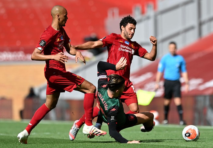 LIVERPOOL, ENGLAND - JULY 05: Jack Grealish of Aston Villa is brought down by Alex Oxlade-Chamberlain of Liverpool and Fabinho of Liverpool during the Premier League match between Liverpool FC and Aston Villa at Anfield on July 05, 2020 in Liverpool, England.Football Stadiums around Europe remain empty due to the Coronavirus Pandemic as Government social distancing laws prohibit fans inside venues resulting in games being played behind closed doors. (Photo by Shaun Botterill/Getty Images)