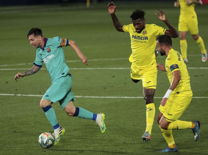 Barcelonas Lionel Messi, left, runs past Villareals Andre-Frank Zambo Anguissa, center, and Villarreals Mario Gaspar during the Spanish La Liga soccer match between FC Barcelona and Villareal at La Ceramica stadium in Villareal, Spain, Sunday, July 5, 2020. (AP Photo/Jose Miguel Fernandez)