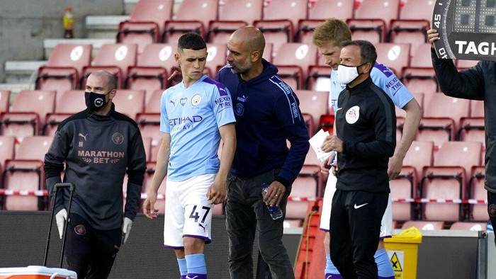 Manchester Citys head coach Pep Guardiola talks with substitute player Phil Foden during the English Premier League soccer match between Southampton and Manchester City at St. Marys Stadium in Southampton, England, Sunday, July 5, 2020. (AP Photo/Will Oliver,Pool)