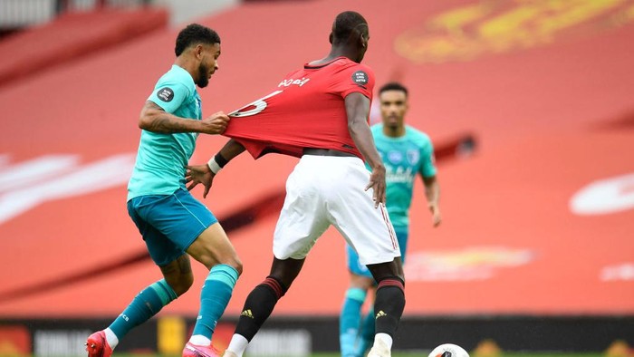 MANCHESTER, ENGLAND - JULY 04: Joshua King of AFC Bournemouth pulls the shirt of Paul Pogba of Manchester United during the Premier League match between Manchester United and AFC Bournemouth  at Old Trafford on July 04, 2020 in Manchester, England. Football Stadiums around Europe remain empty due to the Coronavirus Pandemic as Government social distancing laws prohibit fans inside venues resulting in all fixtures being played behind closed doors. (Photo by Peter Powell/Pool via Getty Images)