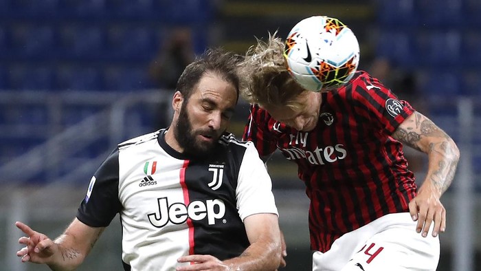 AC Milans Simon Kjaer, right, jumps for the ball with Juventus Gonzalo Higuain during the Serie A soccer match between AC Milan and Juventus at the San Siro stadium, in Milan, Italy, Tuesday, July 7, 2020. (AP Photo/Antonio Calanni)