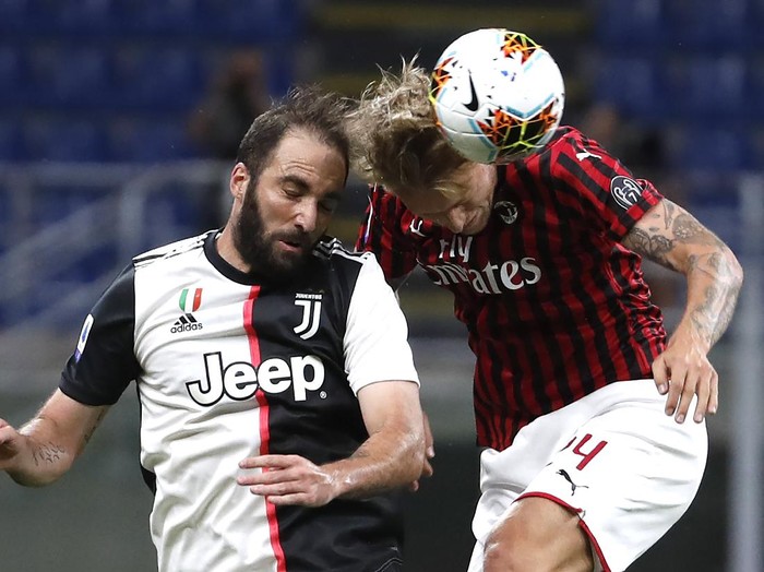 AC Milans Simon Kjaer, right, jumps for the ball with Juventus Gonzalo Higuain during the Serie A soccer match between AC Milan and Juventus at the San Siro stadium, in Milan, Italy, Tuesday, July 7, 2020. (AP Photo/Antonio Calanni)