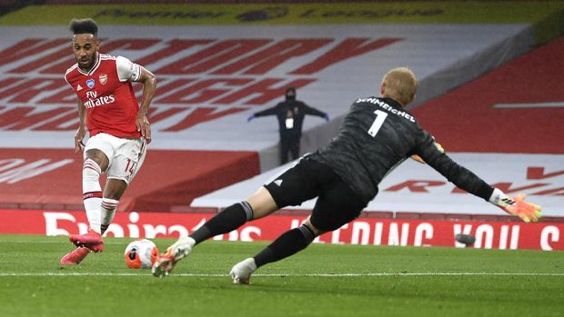 Arsenal's Pierre-Emerick Aubameyang kicks the ball past Leicester's goalkeeper Kasper Schmeichel to score his team's first goal during the English Premier League soccer match between Arsenal and Leicester at Emirates Stadium in London, England, Tuesday, July 7, 2020. (AP Photo/Shaun Botterill,Pool)